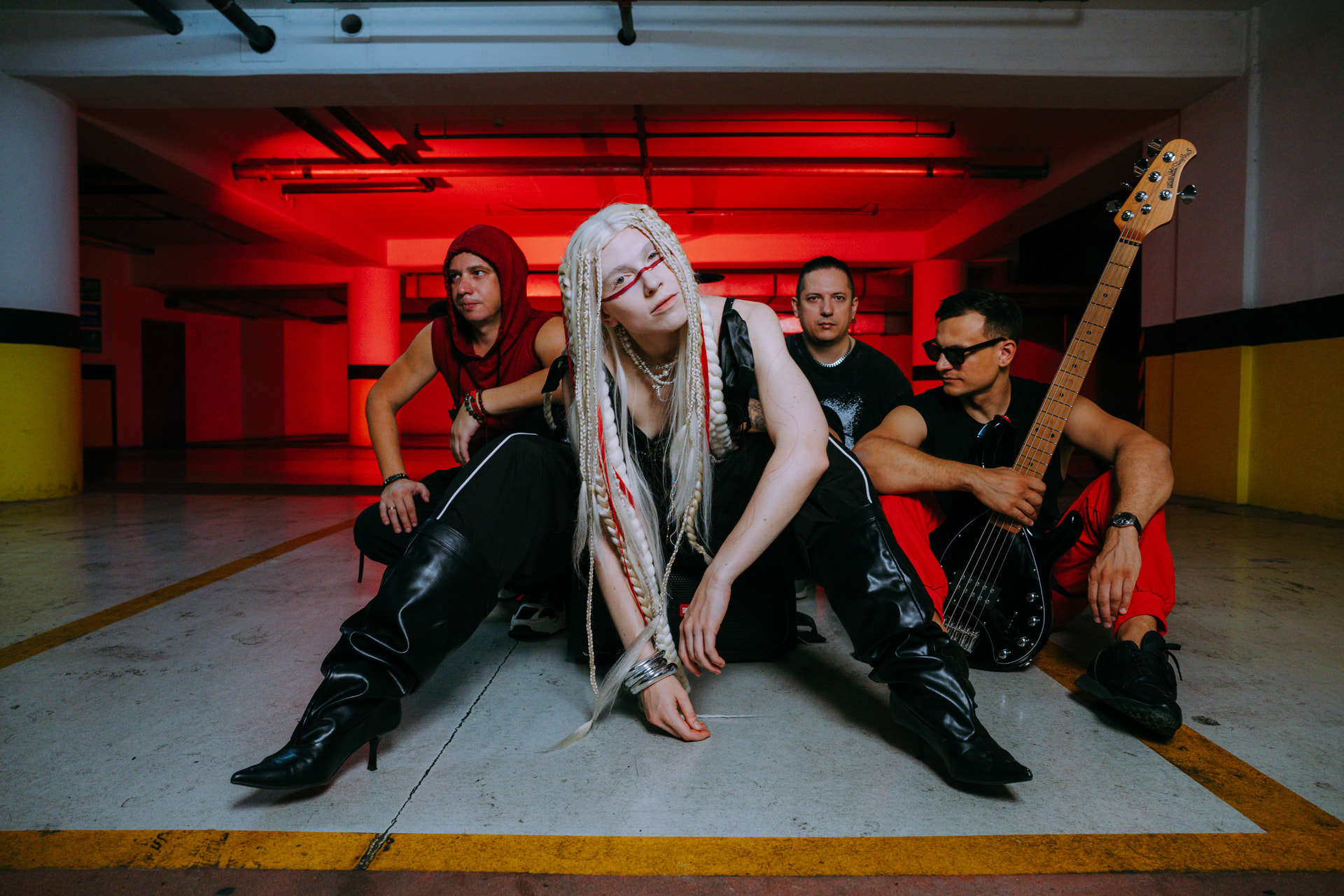 ANAEVE band photo with vocalist seated in front and three members behind in a red-lit garage