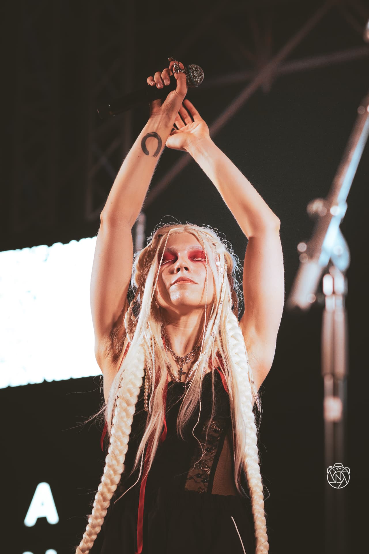 ANAEVE vocalist with long braids raising a microphone on stage