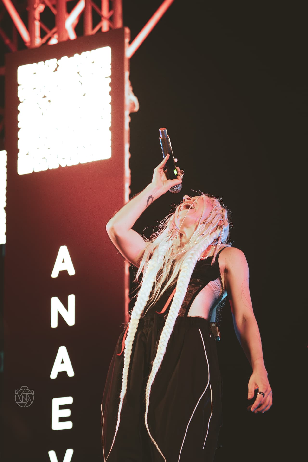 ANAEVE vocalist singing into a microphone beside the ANAEVE light sign